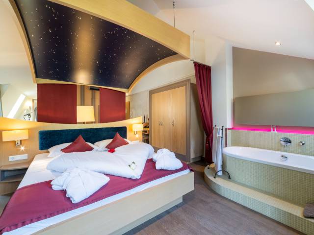 Innenansicht Suite mit Doppelbett und freier Badewanne im Zimmer