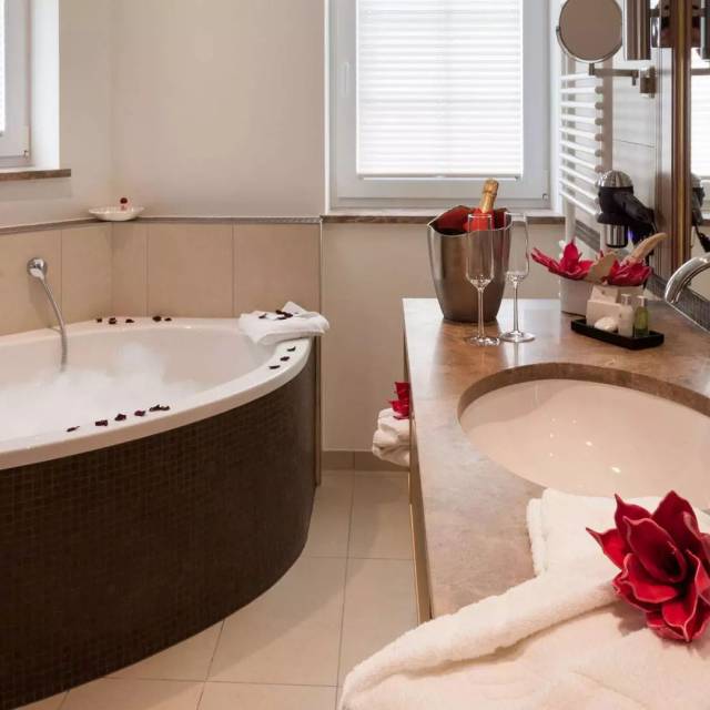 Innenansicht Badezimmer mit Rosenblättern und Sekt