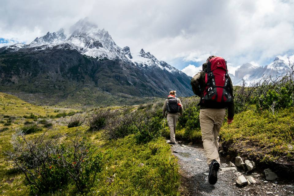 Wanderer laufen mit Ricksäcken einen Wanderweg entlang